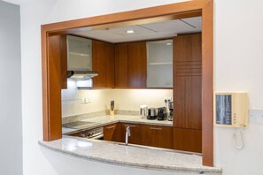 A compact kitchen with wooden cabinets, a built-in stove, and a coffee maker. - Sophisticated and Elegant 2BR in Downntown Dubai (Dubai)