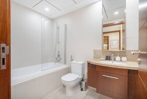 A modern bathroom with a bathtub, toilet, and vanity.