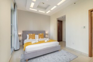 A modern hotel room with a large bed, bedside tables, a nightstand, and a ceiling light fixture. - Sophisticated and Elegant 2BR in Downntown Dubai (Dubai)