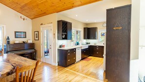 Una cucina con pavimento in legno, mobili scuri, un pianoforte e un'area pranzo con tavolo e sedie in legno.
