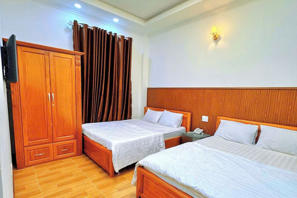 Une chambre d’hôtel avec deux lits, une armoire en bois et un luminaire au plafond.