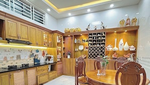 A modern kitchen with wooden cabinets, a marble floor, and a dining area with a wooden table and chairs. - Hostel Nha Tho (Lam Vien - Da Lat)