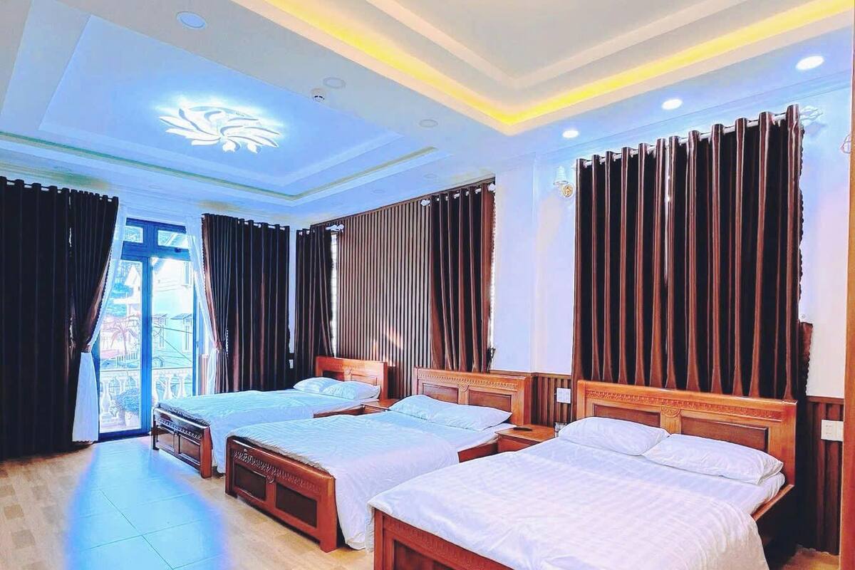 Une chambre d’hôtel avec deux lits, une grande fenêtre et un plafond agrémenté d’un éclairage décoratif.