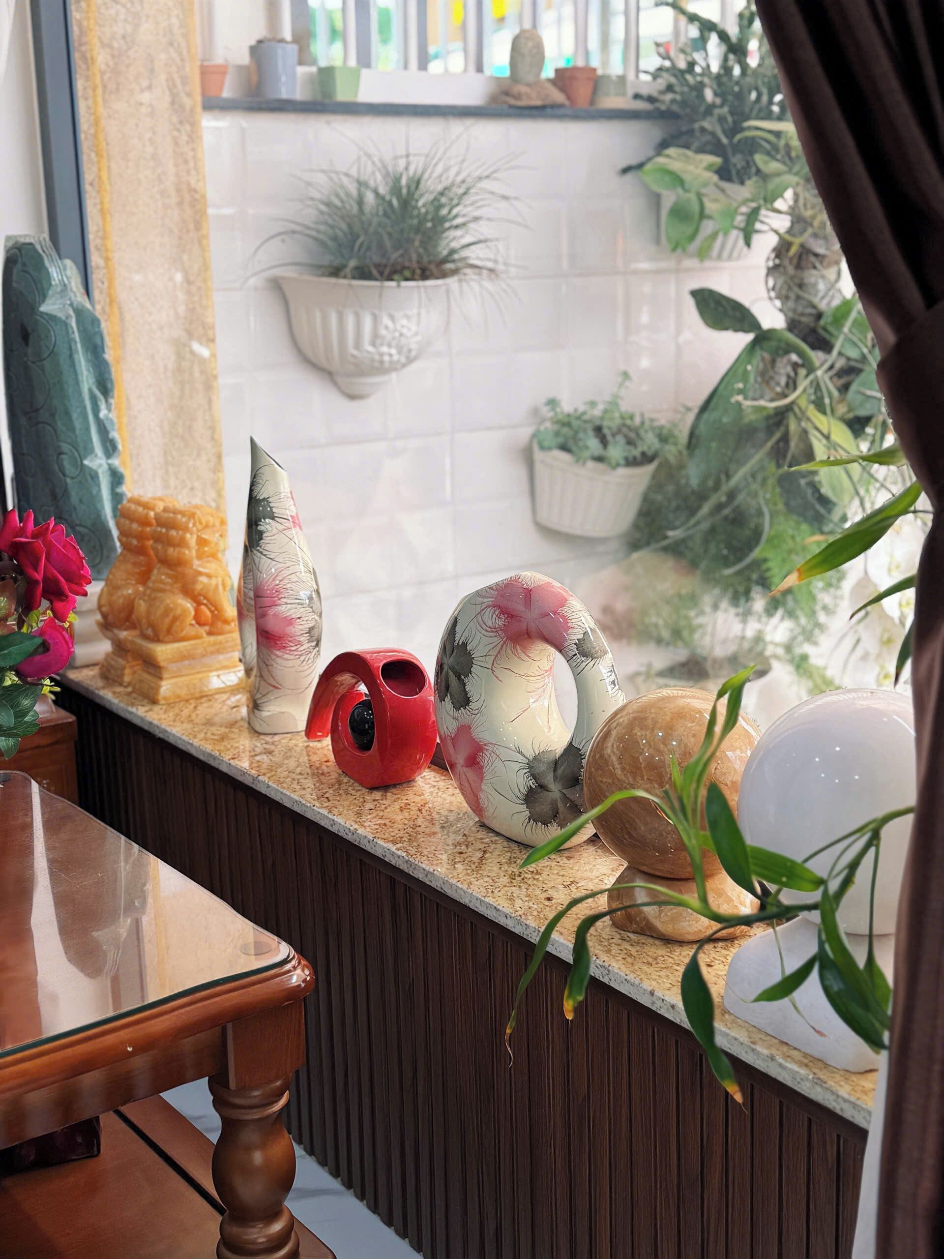 A kitchen counter with decorative items, a potted plant, and a window with a view of the outside.