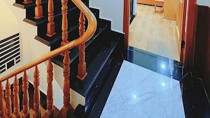 A staircase with wooden balusters leading to a room with a bed, bedside table, and a mirror. - Hostel Nha Tho (Lam Vien - Da Lat)