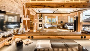 A modern kitchen with a large stove, wooden cabinets, and a dining area with a table and chairs. - Chalet GM in Brand With 5 Bedrooms and 4 Bathrooms (Brand)