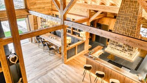 A spacious wooden interior with a high ceiling, a dining area with multiple tables, and a kitchen with modern appliances. - Chalet GM in Brand With 5 Bedrooms and 4 Bathrooms (Brand)