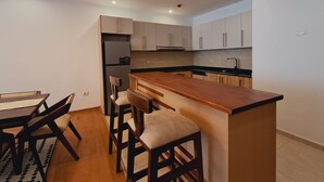 Una cocina moderna con armarios de madera, una isla central y un comedor con mesa y sillas.