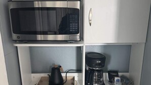Una cuineta compacta amb microones, cafetera i nevereta petita.