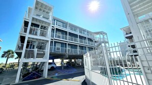 A multi-story building with balconies, a pool area, and a gated entrance. - Sunchase 204 | Pool & Hot Tub | Steps to the Beach (Gulf Shores)