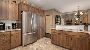 A kitchen with wooden cabinets, a stainless steel refrigerator, a granite countertop, and a stone backsplash. - Stunning Mountain Retreat W/Views|Private Hot Tub (Tabernash)
