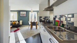 A modern kitchen with a stainless steel sink, a dining area with a table and chairs, and a living room with a sofa and a rug. - Sleeps6- FamilyFriendly- FreeParking- 3Br (Stafford)