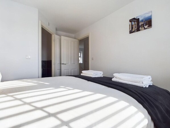 Relax in a serene space with a large bed, framed artwork, and clean lines.