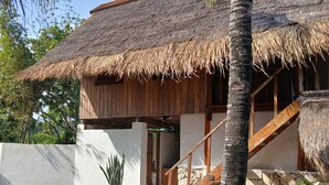 Un edificio con techo de paja y una escalera de madera que lleva a una puerta.