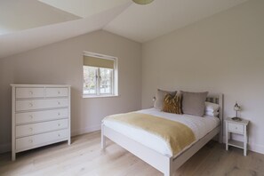 A bedroom with a bed, a dresser, a nightstand, and a window.