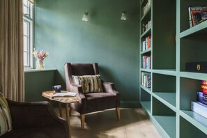A cozy reading nook with a plush armchair, a small side table, and a bookshelf filled with books.