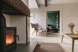 A cozy living room with a fireplace, a comfortable armchair, and a bookshelf.
