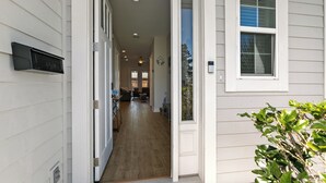 Un pasillo con piso de madera que conduce a una sala de estar con ventilador de techo y vistas al exterior.