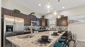 Una cocina moderna con una isla central, electrodomésticos de acero inoxidable y armarios de madera oscura.