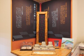 Esposizione di calligrafia e opere d'arte tradizionali giapponesi, tra cui un'opera incorniciata e un piccolo dipinto con una veduta costiera.