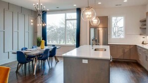 A modern kitchen with a central island, pendant lighting, and large windows. - Encore Estates - Rooftop deck & skyline views (Nashville)