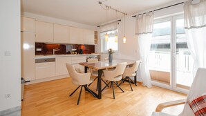 Une cuisine moderne avec un coin repas, un plancher en bois et une vue sur l’extérieur.