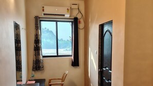 Una camera d'albergo compatta con un letto, una scrivania, una sedia e una finestra vista all'esterno.