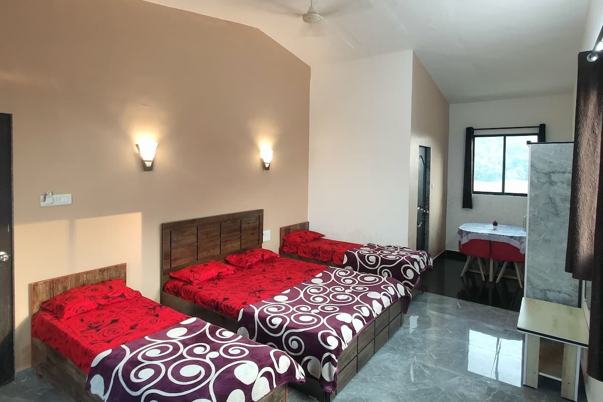 A hotel room with two beds, a small table, a mirror, and a window.