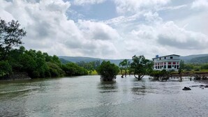 Vista sul fiume con un edificio a destra, immerso nel verde e alberi.