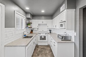 A kitchen with white cabinets, a microwave, a toaster, and a sink.