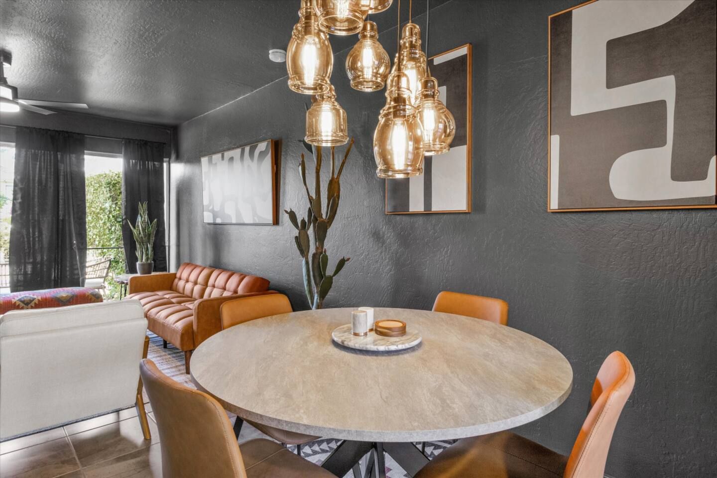 Un comedor moderno con una mesa redonda, asientos de cuero e iluminación colgante.