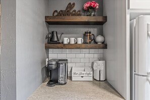 A kitchen with a coffee station, including a Keurig coffee maker, a French press, and a coffee mug.