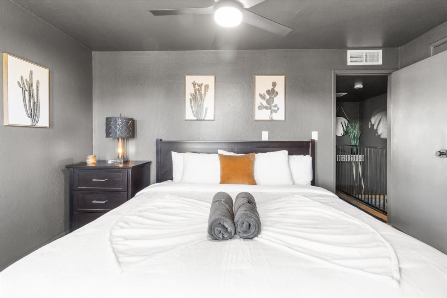 Una habitación de hotel con cama, mesita de noche, lámpara y cuadros en las paredes.