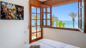 Une chambre avec une grande fenêtre donnant sur la mer et les palmiers.