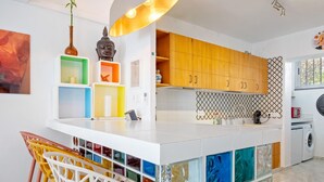 Une cuisine moderne dotée d’un îlot central, de meubles en bois, d’un évier et d’un lave-linge.