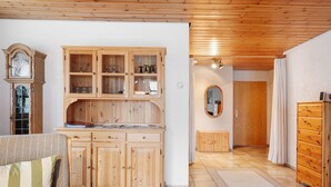A room with wooden cabinets, a clock, a mirror, and a sofa. - Apartment 'Am Blaubeerhang' with Mountain View, Private Terrace and Wi-Fi (Sankt Blasien)