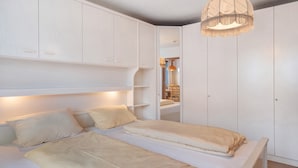 A bedroom with a bed, bedside tables, a wardrobe, and a hanging light fixture. - Apartment 'Am Blaubeerhang' with Mountain View, Private Terrace and Wi-Fi (Sankt Blasien)