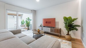 Een moderne woonkamer met een flatscreen televisie, een bank, een salontafel en een grote potplant.
