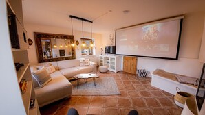 A living room with a sofa, coffee table, and a large screen for presentations. - Apartment 'Gemütliche Wohnung' with Mountain View, Shared Terrace and Wi-Fi (Anger)