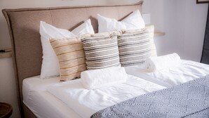 A neatly made bed with a striped pillow, a plain pillow, and a folded towel. - Apartment 'Gemütliche Wohnung' with Mountain View, Shared Terrace and Wi-Fi (Anger)