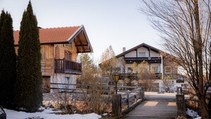 A wooden building with a red-tiled roof, a stone wall, and a wooden fence. - Apartment 'Gemütliche Wohnung' with Mountain View, Shared Terrace and Wi-Fi (Anger)
