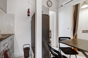 Una cocina con una mesa de comedor, sillas, un reloj y un extintor.