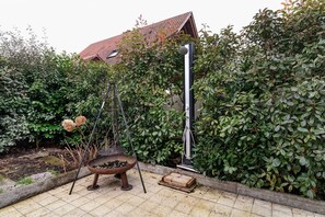 Um jardim com lareira de metal, uma caixa de madeira e um poste de metal.