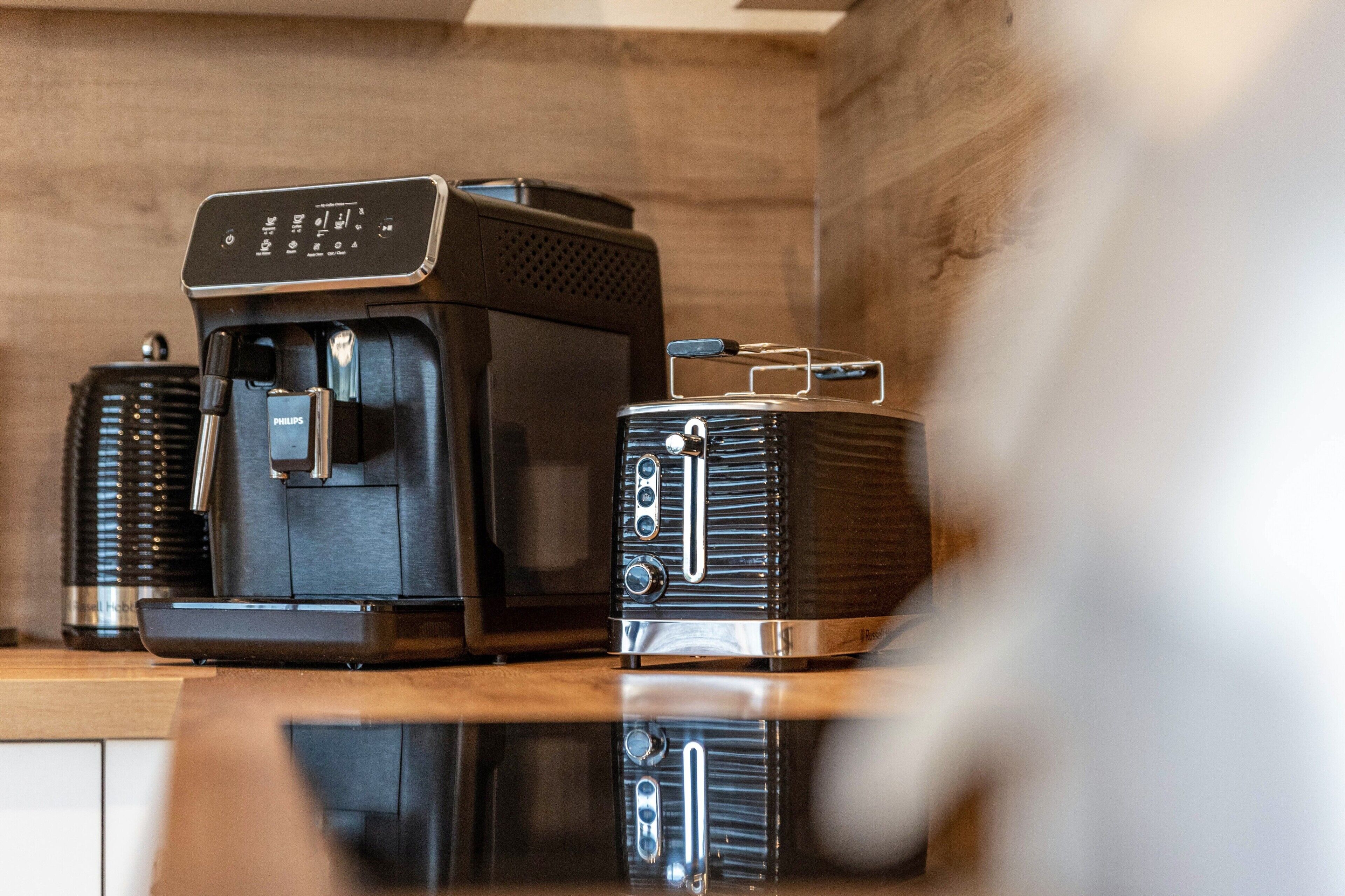 Une machine à café et un grille-pain sont posés sur un plan de travail en bois.