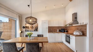 Une cuisine moderne avec des armoires blanches, un plan de travail en bois et un four encastré.