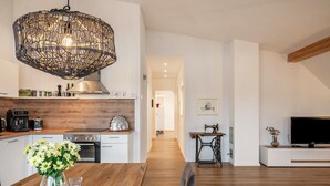 Une cuisine moderne avec des armoires blanches, un plan de travail en bois et un luminaire suspendu.