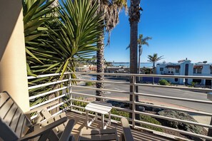 A balcony with a view of a street, palm trees, and buildings. - Capitola Village Condo - 1 min walk to beach (Capitola)