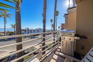 Ein Balkon mit Grill, Palmen und Blick auf Strand und Meer.