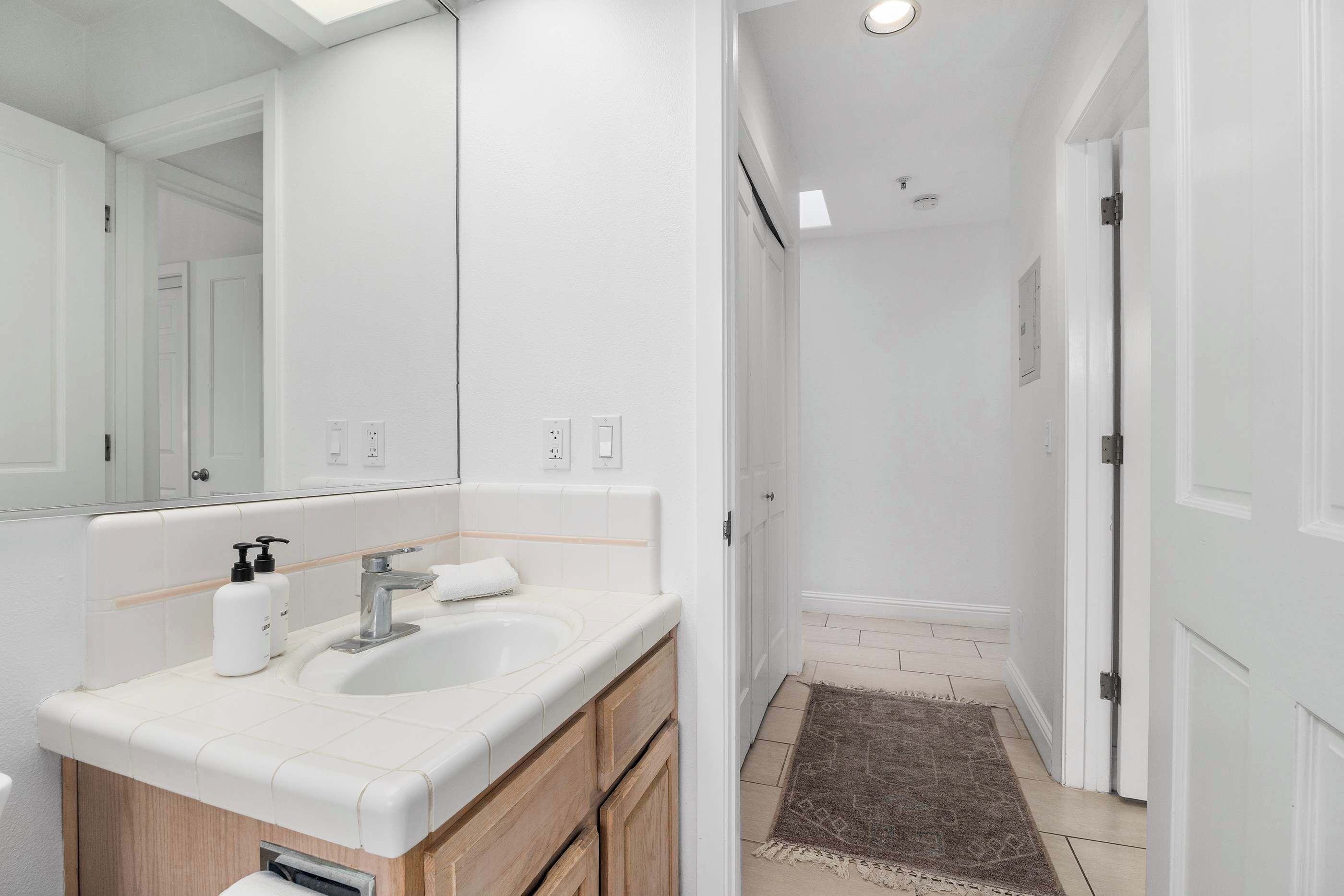 A bathroom with a white sink, mirror, and wooden cabinets.