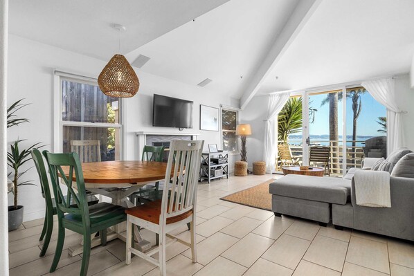A spacious living area with a dining table, chairs, a sofa, and a TV.